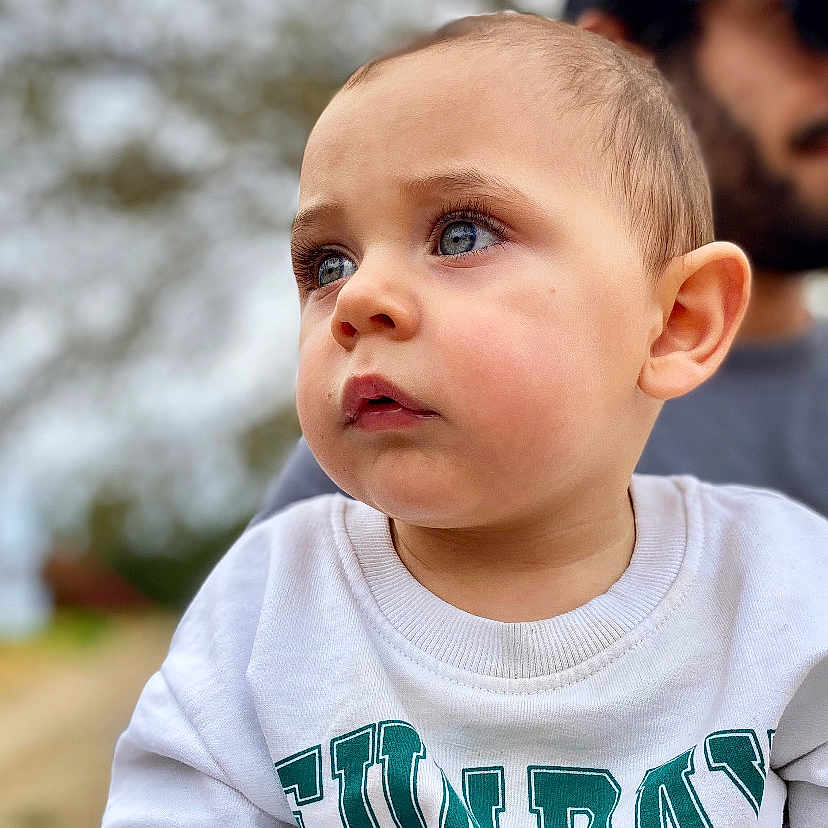 Raphaël a rejoint le concours — aidez-le/la à gagner de superbes lots ! background, beard, blue_eyes, cap, casual_clothing, child, closeup, curious, daylight, face, graphic, man, nature, outdoor, person, portrait, soft_expression, sunglasses, sweatshirt, toddler