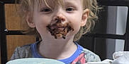 Dennis joined the competition — help win amazing prizes! toddler, child, chocolate, messy_face, indoor, table, cup, candle, clothing, hair, face, smile, person, seat, wooden_furniture, background, light, expression, curly_hair, casual