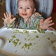 Oliver is registered to the contest to win money with this photo: baby, high_chair, messy, food, green_food, smiling, child, happy, hands, face, indoor, meal, clothing, cute, fun, playful, feeding, kitchen, toddler, expression