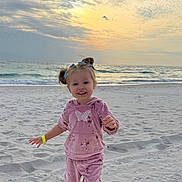Leilani is registered to the contest to win money with this photo: child, toddler, beach, sand, ocean, waves, sunset, sky, clouds, smile, pink_outfit, hoodie, sweatpants, crocs, hair_buns, wristband, footprints, horizon, playful, portrait