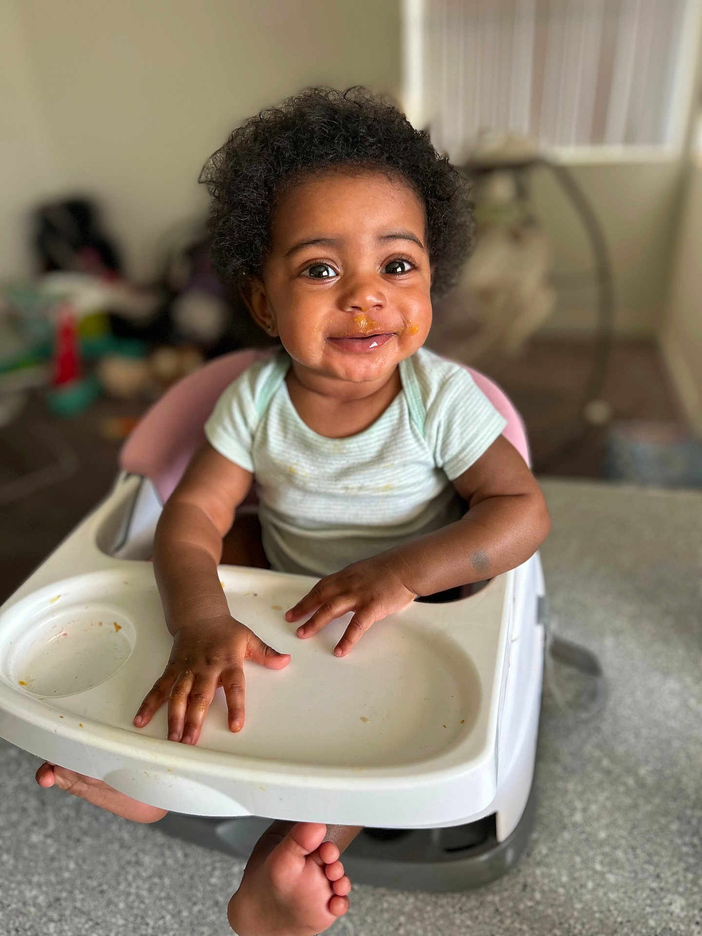 Promise is registered to the contest to win money with this photo: baby, high_chair, smile, messy_face, food, indoor, child, happy, curly_hair, person, skin, hand, foot, table, clothing, infant, expression, seat, cute, portrait