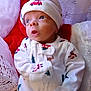 Paxton is registered to the contest to win money with this photo: baby, infant, pajamas, hat, face, expression, blue_eyes, blanket, red, white, holiday, christmas, cozy, soft_texture, person, child, cute, indoors, portrait, newborn