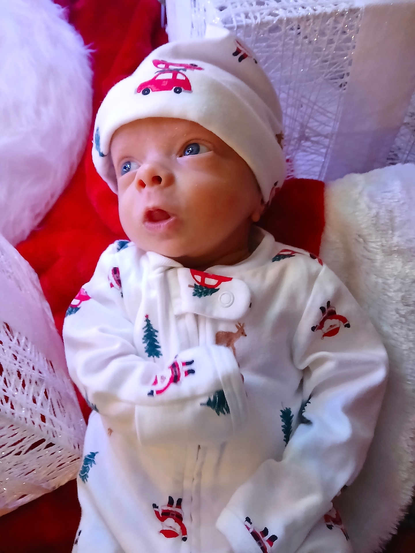 Paxton is registered to the contest to win money with this photo: baby, infant, pajamas, hat, face, expression, blue_eyes, blanket, red, white, holiday, christmas, cozy, soft_texture, person, child, cute, indoors, portrait, newborn