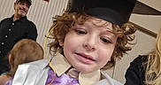 Kolby joined the competition — help win amazing prizes! child, graduation_cap, sash, curly_hair, smile, indoor, person, adult, man, black_shirt, hat, celebration, event, purple_shirt, happy, family, portrait, people, casual_clothing