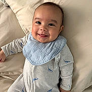 Emiliano joined the competition — help win amazing prizes! baby, smiling, infant, onesie, bib, dinosaur_pattern, bed, pillow, happy, child, cute, portrait, sleepwear, lying_down, indoor, face, skin, head, hand, young