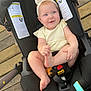 baby, smiling, stroller, headband, blue_eyes, infant, toy, wooden_deck, black_stroller, happy, child, outdoor, foot, clothing, seat, person, cute, summer, playful, baby_girl