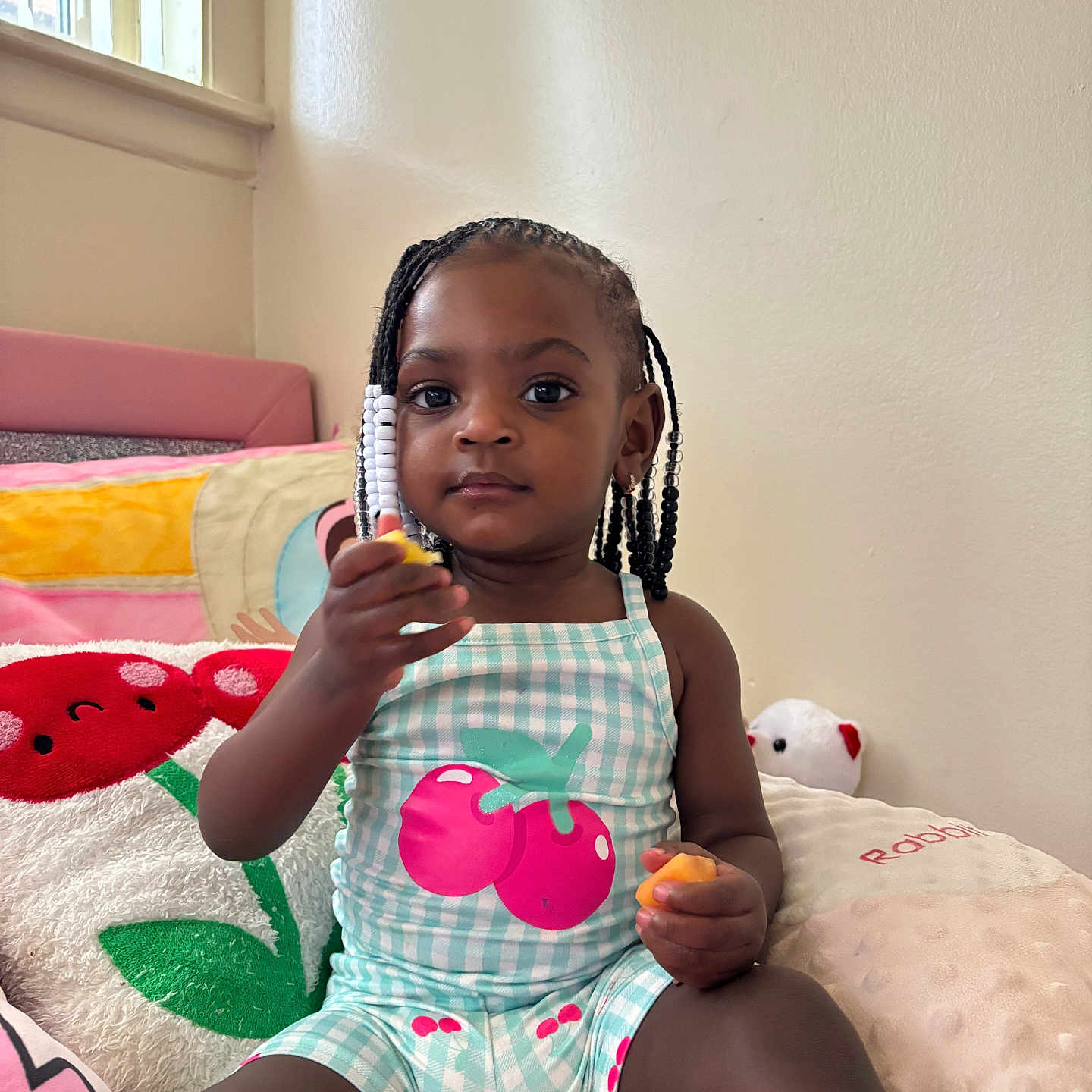Kamira joined the competition — help win amazing prizes! child, toddler, girl, braided_hair, beads, plush_pillow, bedroom, toy, sitting, indoor, cute, clothing, patterned_outfit, window, light, face, person, young_child, comfort, relaxed