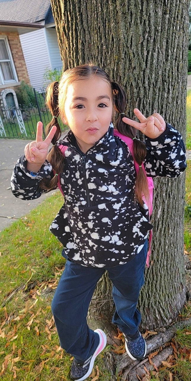 Angelina is registered to the contest to win money with this photo: child, denim, eye, fashion_accessory, finger, gesture, grass, hand, happy, pattern, people_in_nature, person, plant, portrait_photography, sitting, sleeve, thumb, toddler, tree, trunk