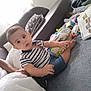 Rafael participe au concours pour gagner de l'argent avec cette photo : baby, child, striped_shirt, denim_shorts, toys, indoor, couch, pillow, carpet, person, sitting, curious, soft_surface, hand, foot, window, blanket, home, expression, furniture