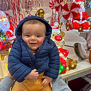 Nolan participe au concours pour gagner de l'argent avec cette photo : baby, candy_cane, celebration, child, christmas, decorations, display, festive, holding, holiday, indoor, joyful, lights, peppermint, person, puffer_jacket, reindeer, santa_claus, smiling, winter_clothing