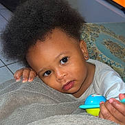 Maylone a rejoint le concours — aidez-le/la à gagner de superbes lots ! toddler, child, toy, blanket, afro_hair, indoor, television, cartoon, face, hand, earrings, floor, tile, clothing, person, portrait, cute, expression, love, home