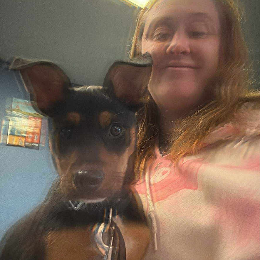 Sassy is registered to the contest to win money with this photo: person, dog, indoor, selfie, smile, leash, collar, ear, light, wall, casual_clothing, hair, face, young_adult, pet, animal, holding, portrait, blur, ceiling_light