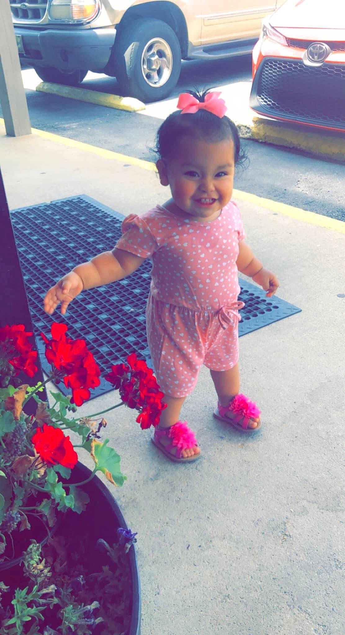 Katherine is registered to the contest to win money with this photo: child, facial_expression, flooring, flower, fun, happy, joy, leisure, magenta, organ, person, petal, photograph, pink, plant, public_space, red, smile, standing, tire