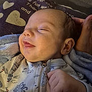 Dakota is registered to the contest to win money with this photo: baby, infant, smile, sleeping, onesie, hand, blanket, heart, face, head, cozy, child, cute, soft, resting, closeup, portrait, warm, comfort, newborn
