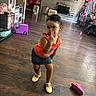 Laneigh is registered to the contest to win money with this photo: casual_clothing, child, decor, denim_skirt, fireplace, flooring, furniture, girl, home_interior, indoors, living_room, orange_top, person, pink_shoe, playful, posing, smile, toys, wooden_floor, yellow_shoes