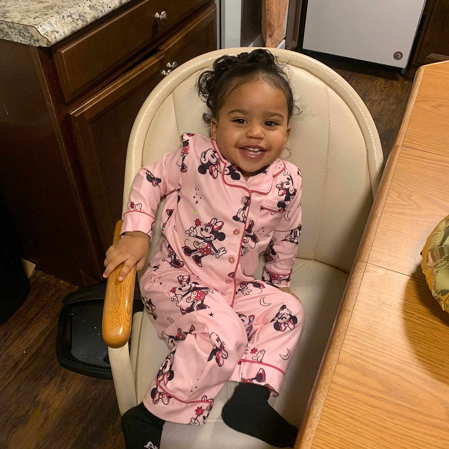 Laneigh is registered to the contest to win money with this photo: black_socks, chair, child, cozy, curly_hair, cute, granite_countertop, happy, indoor, kitchen, minnie_mouse, pajamas, person, pink, seat, smiling, table, toddler, wooden_cabinet, wooden_floor