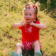 Blakely joined the competition — help win amazing prizes! child, girl, toddler, smiling, outdoors, grass, wildflowers, garden, portrait, sitting, red_shirt, checked_shorts, hair_bows, sunlight, summer, playful, happy, shoes, nature, photography