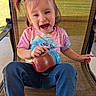casual_clothing, chair, child, cute, daytime, denim_jeans, fun, happy, outdoor, person, pigtails, playful, portrait, seat, sippy_cup, smiling, sunlight, tie_dye_shirt, toddler, young_child