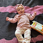 Lakelynn joined the competition — help win amazing prizes! baby, infant, blanket, clothing, headband, face, person, lying_down, diaper_wipes, toy, pink, cream, patterned_pants, soft_texture, indoor, cute, smile, child, happy, cozy