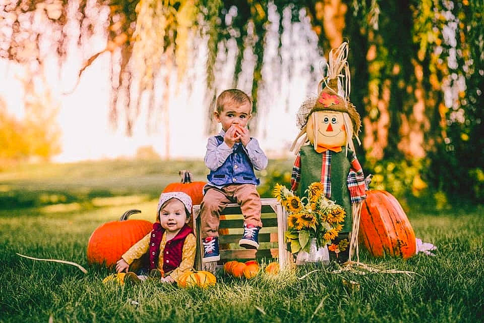 Mateo is registered to the contest to win money with this photo: autumn, calabaza, child, family, fun, grass, happy, headwear, people, people_in_nature, person, photograph, photography, plant, playing_with_kids, pumpkin, sibling, smile, sunlight, toddler