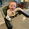 Cooper is registered to the contest to win money with this photo: baby, child, high_chair, smile, happy, sock, foot, clothing, dog_print, indoor, table, couch, floor, bag, home, person, face, seat, wood_floor, playful