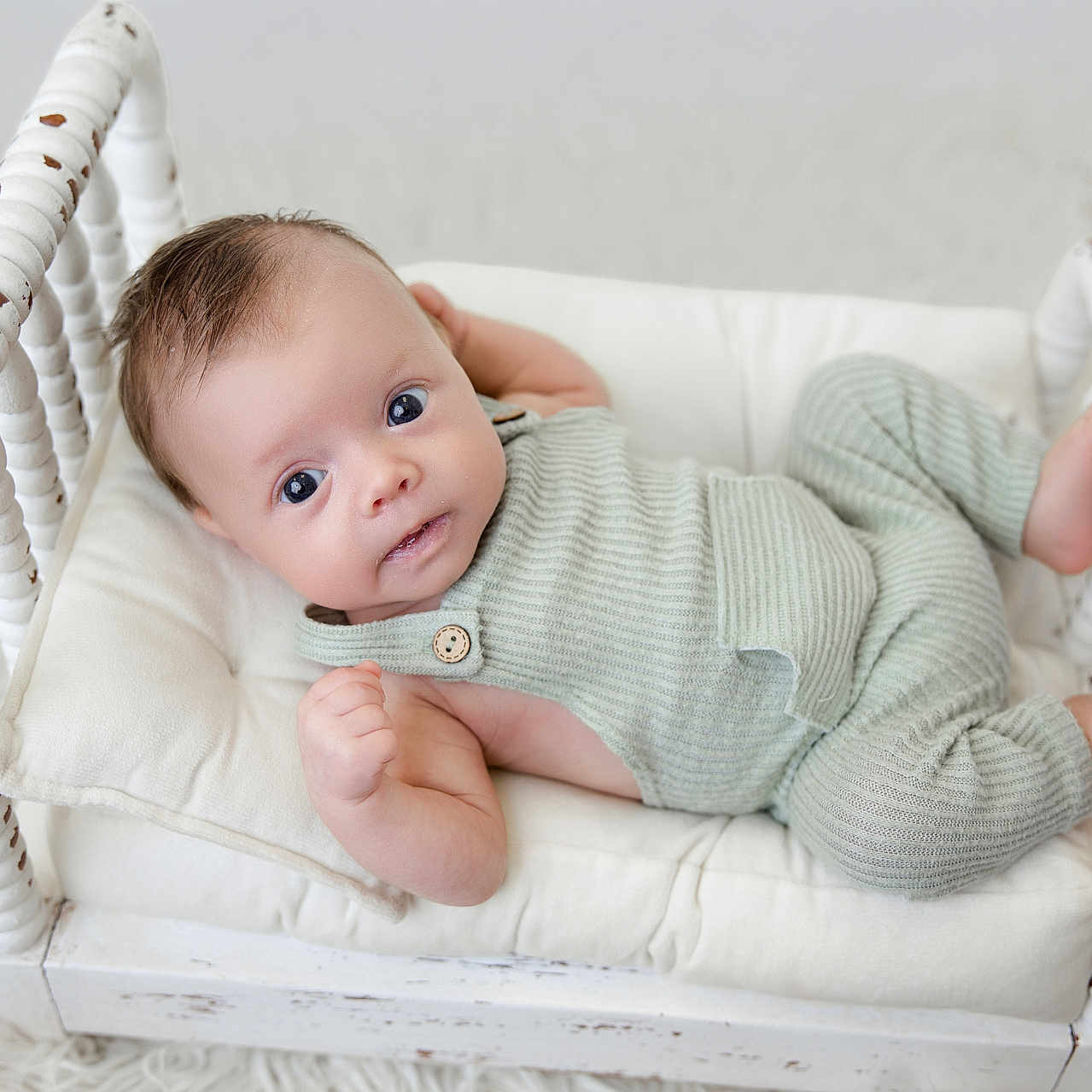 Bennett is registered to the contest to win money with this photo: baby, infant, cradle, wooden_furniture, knitted_clothing, mint_green, white_background, soft_texture, curious_eyes, lying_down, cozy, cute, portrait, child, small_baby, indoor, peaceful, resting, cushion, furniture