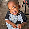 child, boy, toddler, smiling, portrait, outdoor, wooden_deck, chair, railing, greenery, short_hair, gold_chain, gray_shirt, black_sleeves, black_pants, standing, hands, teeth, happy, photography