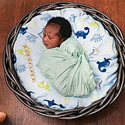 Ugochukwu is registered to the contest to win money with this photo: newborn, baby, swaddle, basket, blanket, dinosaur_pattern, wooden_floor, sleeping, cute, infant, scrabble_tiles, name, cozy, portrait, peaceful, child, soft, wrapped, indoor, resting