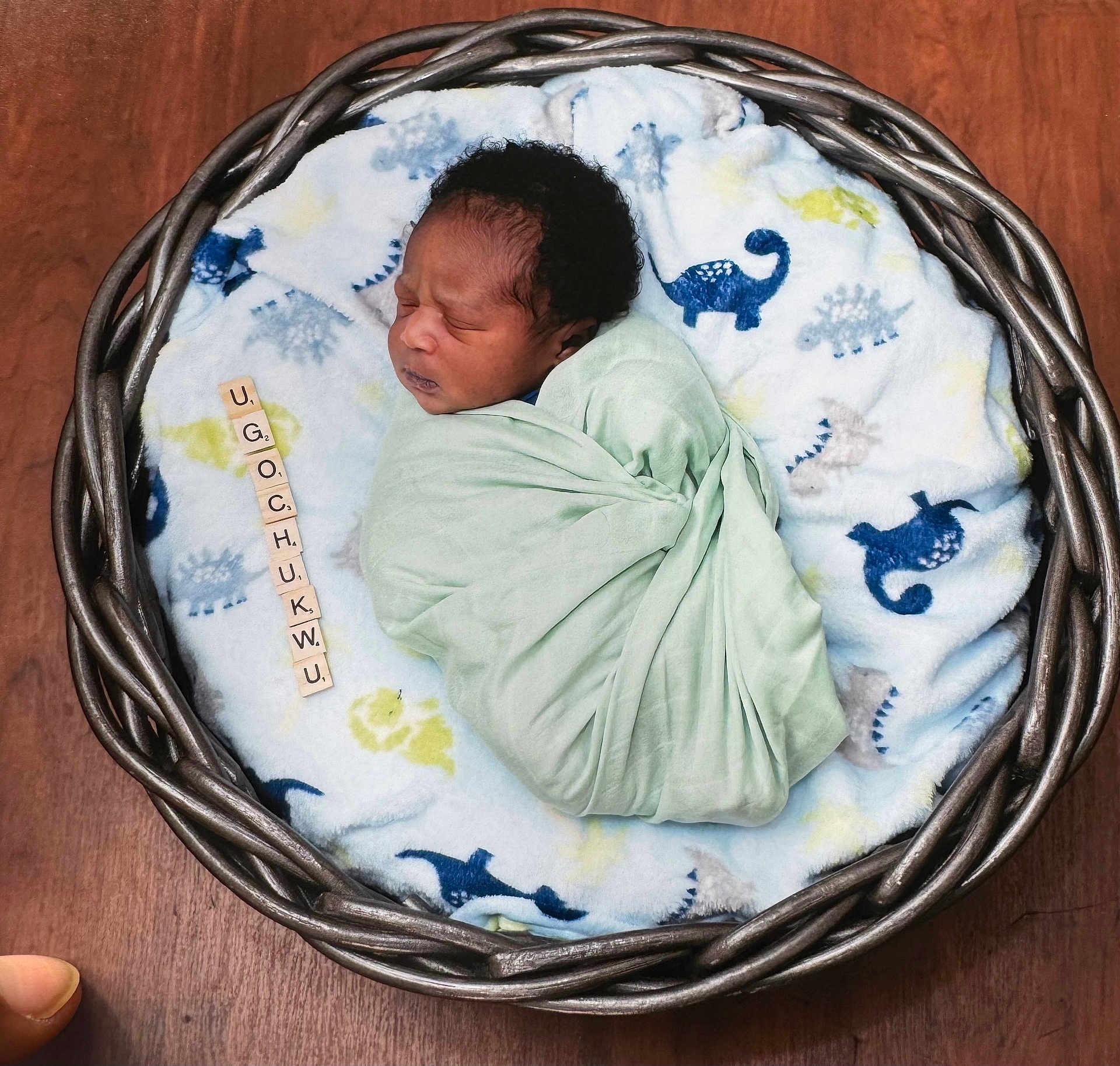 Ugochukwu is registered to the contest to win money with this photo: newborn, baby, swaddle, basket, blanket, dinosaur_pattern, wooden_floor, sleeping, cute, infant, scrabble_tiles, name, cozy, portrait, peaceful, child, soft, wrapped, indoor, resting