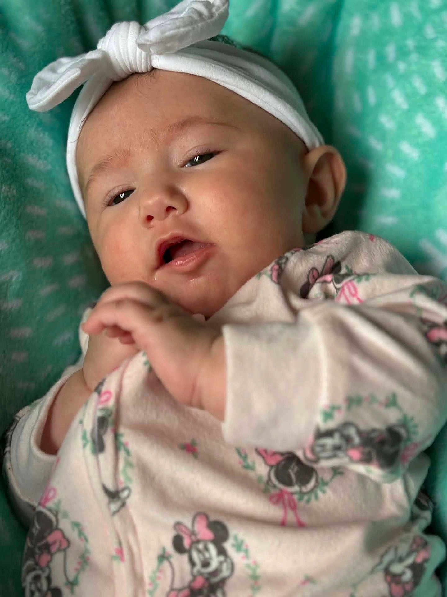 Mckinnleigh is registered to the contest to win money with this photo: baby, blanket, bow, child, closeup, clothing, cute, expression, face, hands, headband, indoor, infant, lying_down, minnie_mouse, onesie, portrait, sleepwear, soft, teal