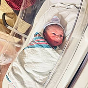 Faraj joined the competition — help win amazing prizes! newborn, baby, hospital, bassinet, swaddled, blanket, hat, infant, sleeping, bed, medical, patient, newborn_baby, crib, wrapped, person, face, cute, small, indoors