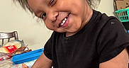 Malik joined the competition — help win amazing prizes! child, toddler, smiling, winking, black_tshirt, indoor, hair, happy, playing, table, chair, toy, colorful, person, face, cute, expression, young, skin, casual