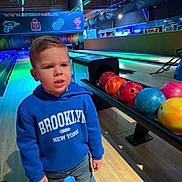 Milann participe au concours pour gagner de l'argent avec cette photo : blue_clothing, bowling_alley, bowling_balls, boy, casual_clothing, child, colorful, expression, face, hoodie, indoor, jeans, lanes, neon_lights, person, recreation, shoes, sport, standing, wooden_floor