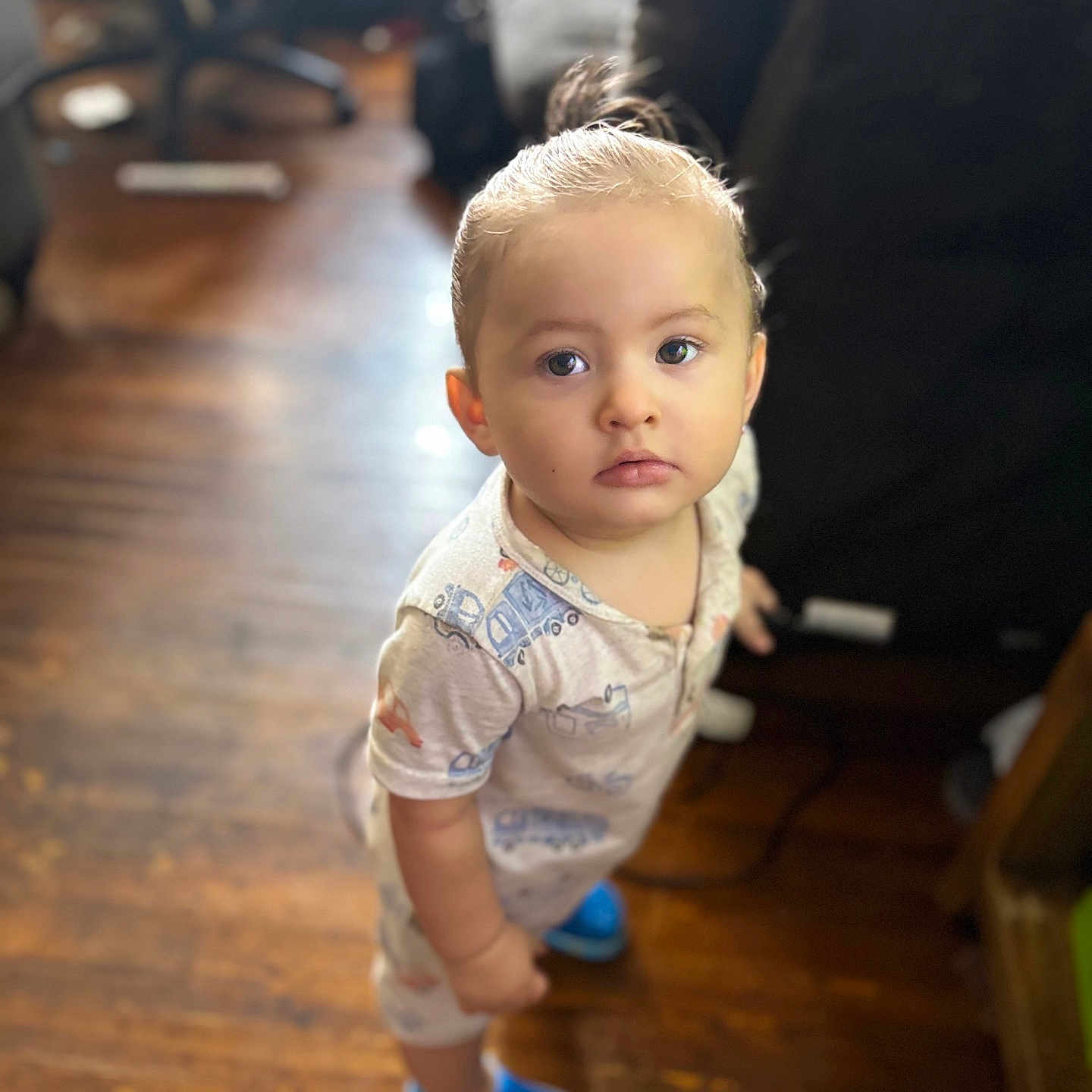 Jadeziah joined the competition — help win amazing prizes! blue_shoes, blurred_background, casual_clothing, child, curious, cute, expression, face, footwear, furniture, hair_tied, home, indoor, looking_up, pajamas, person, standing, toddler, wooden_floor, young_child
