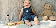 Roman is registered to the contest to win money with this photo: baby, denim_overalls, smiling, teddy_bear, blocks, flower, jar, blanket, patterned_background, happy, child, sitting, indoor, cute, playful, toys, portrait, infant, soft_light, cozy