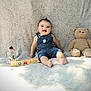 baby, denim_overalls, smiling, teddy_bear, blocks, flower, jar, blanket, patterned_background, happy, child, sitting, indoor, cute, playful, toys, portrait, infant, soft_light, cozy