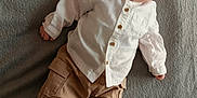 Mathéo a rejoint le concours — aidez-le/la à gagner de superbes lots ! baby, infant, child, milestone_card, white_shirt, tan_pants, shoes, blanket, gray_background, lying_down, curious_expression, portrait, indoors, casual_clothing, one_month_old, soft_texture, cute, newborn, small_hands, milestone