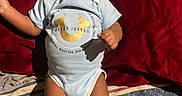 Dahari joined the competition — help win amazing prizes! baby, infant, smiling, blue_onesie, socks, blanket, red_background, happy, portrait, child, cute, lying_down, indoor, clothing, face, person, young_child, joyful, expression, toddler