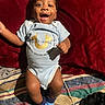 baby, infant, smiling, blue_onesie, socks, blanket, red_background, happy, portrait, child, cute, lying_down, indoor, clothing, face, person, young_child, joyful, expression, toddler