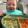 Reign is registered to the contest to win money with this photo: baby, child, high_chair, bib, food, cheese, tomato_sauce, messy, smiling, happy, kitchen, plate, meal, toddler, feeding, indoor, person, face, table, chair