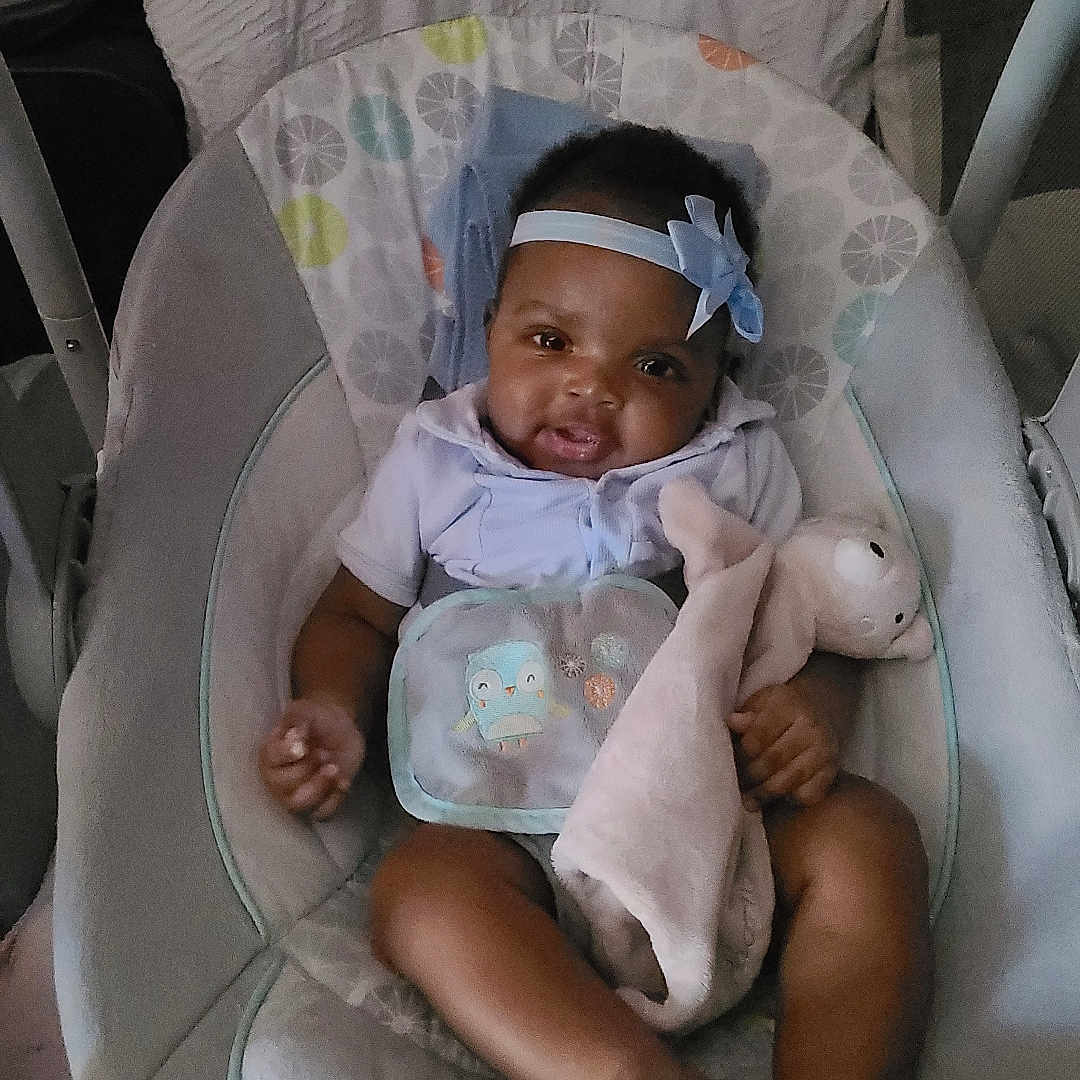 Adaeze is registered to the contest to win money with this photo: baby, baby_seat, bow, child, clothing, comfort, cushion, cute, fabric, foot, hand, happy, headband, indoors, infant, person, plush_toy, portrait, smiling, soft_toys