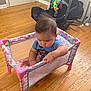 Kenny is registered to the contest to win money with this photo: baby, blue_shirt, bracelet, car_seat, casual, child, concentration, cute, flooring, furniture, home, indoor, infant, pink, playpen, polka_dots, sitting, toy, wooden_floor, young_child