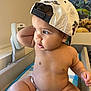 aquarium, arm, baby, baseball_cap, cap, child, chubby, curious, diaper, face, fish, indoor, leg, light, medical_table, poster, room, sitting, skin, toddler