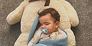 Kenny is registered to the contest to win money with this photo: baby, sleeping, pacifier, blanket, teddy_bear, plush_toy, carpet, indoor, child, cute, cozy, rest, nap, soft, comfort, toy, infant, wrapped, peaceful, sleep