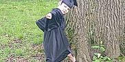 Nickalus is registered to the contest to win money with this photo: child, graduation_gown, graduation_cap, tree, grass, outdoor, nature, pose, playful, young, footwear, greenery, forest_floor, celebration, person, happy, smile, plant, casual, daylight