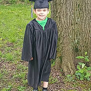Nickalus joined the competition — help win amazing prizes! child, graduation, cap, gown, outdoor, tree, grass, smile, winking, young, footwear, nature, celebration, portrait, person, greenery, shoes, happy, standing, casual