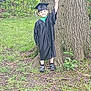 Nickalus joined the competition — help win amazing prizes! child, graduation_gown, graduation_cap, peace_sign, smile, tree, outdoor, grass, greenery, nature, young_child, happy, forest, shoes, standing, celebration, portrait, person, casual, daylight