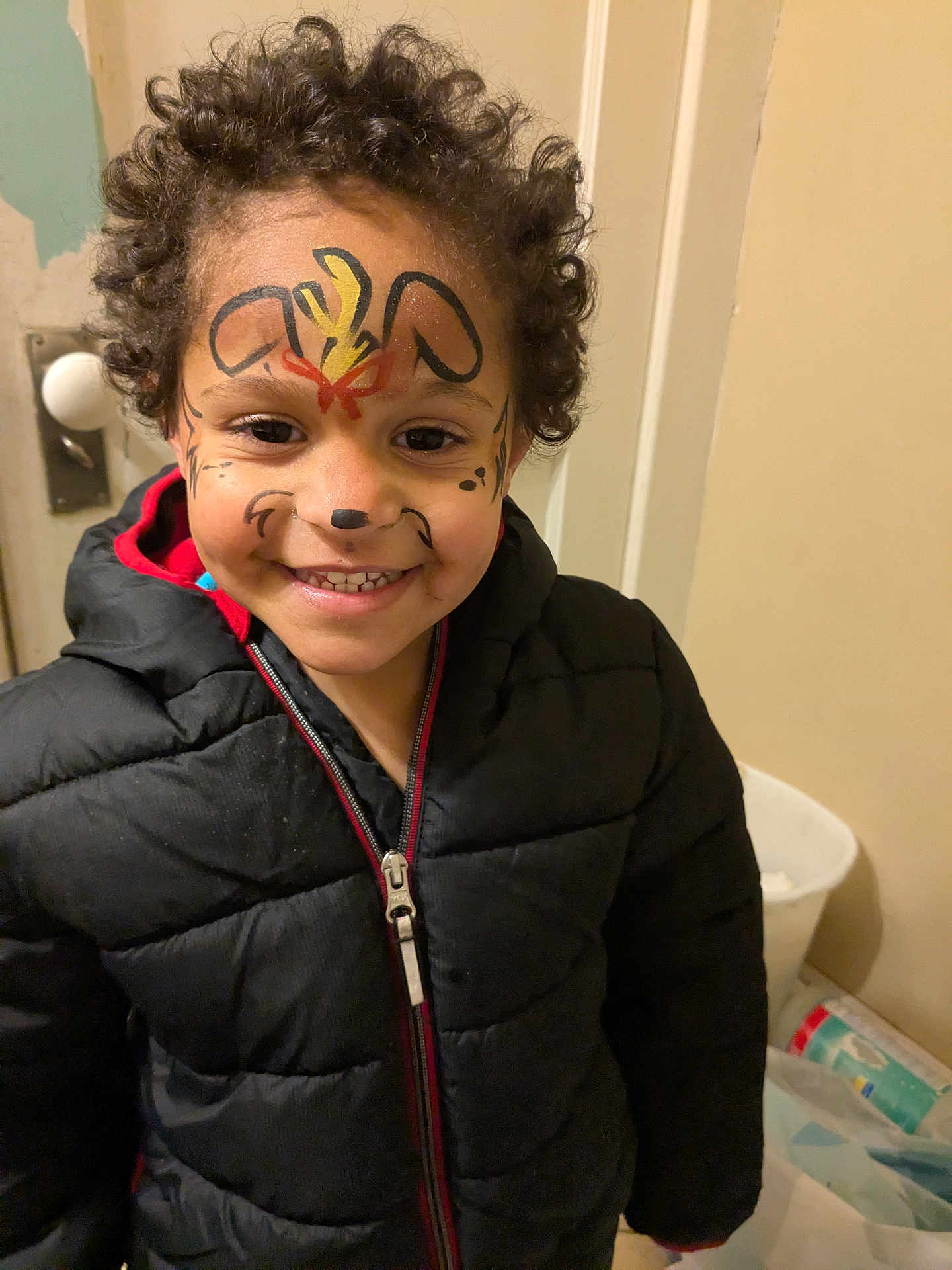 Kyle joined the competition — help win amazing prizes! child, face_paint, smile, curly_hair, jacket, black_jacket, indoor, door, zipper, happy, person, young_child, face, portrait, clothing, warm_clothing, curly_hair_child, fun, painted_face, expression