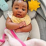 baby, infant, yellow_bow, pink_blanket, plush_toy, sun_plush, star_plush, cloud_plush, baby_nest, cozy, curly_hair, soft_toys, child, cute, smiling, indoors, portrait, blanket, playtime, happy