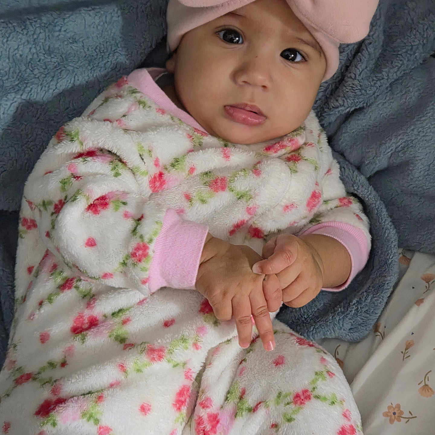 Ailany is registered to the contest to win money with this photo: baby, bed, blanket, child, closeup, cozy, cute, eyes, face, floral_outfit, hands, indoors, infant, looking_at_camera, lying_down, photography, pink_bow, portrait, soft_texture, tongue